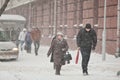 Elderly woman and young man walking through driving snow. Blizzard in the city