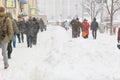 People going along sidewalk among big snow piles. Typical winter