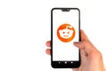 Minsk Belarus - 31 January 2021: Reddit logo on smartphone screen in male hand isolated on white