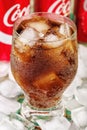 MINSK, BELARUS - JULY 09, 2017: Coca-cola glass with ice close-up and three cans. Vertical photo. Coca-Cola is a carbonated soft d Royalty Free Stock Photo