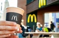 Minsk, Belarus, July 02, 2019: Paper cup of coffee with McDonald`s logo in hands of a woman closeup. A woman is drinking coffee on