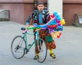 Balloon vendor in an extravagant costume with a bicycle. Sad face