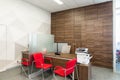 Minsk, Belarus - May 23, 2019: Corner of modern office with white and wooden walls, gray floor, open space area with red Royalty Free Stock Photo