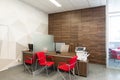 Minsk, Belarus - May 23, 2019: Corner of modern office with white and wooden walls, gray floor, open space area with red Royalty Free Stock Photo