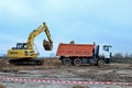 Excavator Komatsu Hybrid HB215LC load the sand to the heavy dump truck MAZ on construction site.