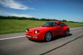 Red Porsche 944 moves along road. Royalty Free Stock Photo
