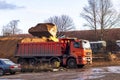 Minsk. Belarus. 2020, November, 24. A big red car is under loading. The loader pours sand into the body Royalty Free Stock Photo