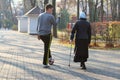 Minsk, Belarus - October 27, 2019: A young man with a football walking near an old woman with a stick in Gorky park