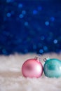 Mint blue and pink Christmas balls on white fur with garland lights on blue bokeh background Royalty Free Stock Photo
