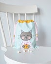 Mint drawstring bag with cute cat applique and marshmallows on chair