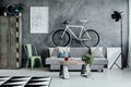 Mint green metal chair next to grey sofa with pillow in dark living room interior with map on empty concrete wall Royalty Free Stock Photo