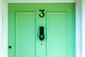 Mint green wooden front door with the house number 3