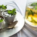 Mint julep cocktails in small pewter cups with pitcher. Spearmint garnish and ice cubes.