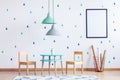 Mint and pastel blue lamps above small table and wooden chairs for kids