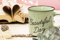 Mint tea mug. On the mug is the inscription of a beautiful day. Nearby lies an open book with heart-shaped pages. Garlands, a Royalty Free Stock Photo