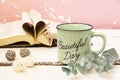 Mint tea mug. On the mug is the inscription of a beautiful day. Nearby lies an open book with heart-shaped pages. Garlands, a Royalty Free Stock Photo