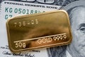 Minted gold bar weighing 50 grams against the background of dollar bill