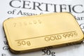 Minted gold bar weighing 50 grams fineness 999.9 on the background of a certificate Royalty Free Stock Photo