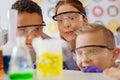 Upbeat teenage classmates watching chemical substance react in flask