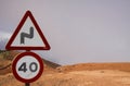 Mirador del Rio - Lanzarote: Close up of Speed limit 40 sign and warning for curves signs above clouds on dry mountain Focus on