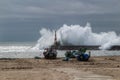 Fishing boats stranded on Aguda beach and Giant waves breaking on the breakwater Royalty Free Stock Photo