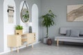 Mirror above wooden cupboard with lamp in grey living room inter