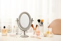 Mirror in antique frame and different cosmetics on dressing table.