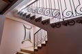 Mirror in a frame with swirls hangs on the wall between the stairs with monograms and metal railings