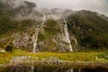 Mirror Lake waterfall. Dark and foggy Fiordland mountains falling water and black lake, Milford Track New Zealand