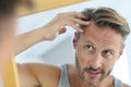 Mirror portrait of man concerned by hair loss