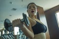 Mirror portrait of young pretty and fit Asian Japanese woman working hard at hotel gym or fitness center lifting dumbbell doing Royalty Free Stock Photo