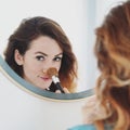 Mirror portrait of a young woman powdering her nose