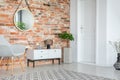 Mirror on red brick wall above white cupboard and grey armchair in living room interior Royalty Free Stock Photo