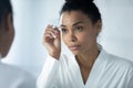 Beautiful young african american woman in bathrobe using tweezers, Royalty Free Stock Photo