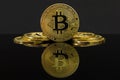 A mirror reflection of a big golden BTC coin. The coin of bitcoin is on a black table and black background. Golden bitcoin