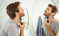 Mirror reflection, grooming and man shaving in the bathroom of a home in the morning for personal hygiene. Electric Royalty Free Stock Photo