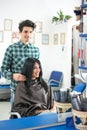 Mirror reflection of hairstylist hairdresser with comb combing hair of female client. Woman in hairdressing beauty salon Royalty Free Stock Photo