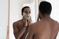 Mirror reflection smiling African American man applying shaving foam Royalty Free Stock Photo