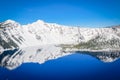 Scenic winter mirror reflection of snowcap mountain and Wizard Island on Crater Lake Royalty Free Stock Photo