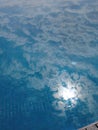 Mirror reflection of the sun, blue sky and clouds in swimming pool, ceramic tiles texture, clear water, reflected, picture in Royalty Free Stock Photo