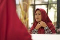 Mirror reflection of young happy and beautiful Muslim woman in traditional hijab adjusting red head scarf in beauty and fashion Royalty Free Stock Photo