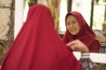 Mirror reflection of young happy and beautiful Muslim woman in traditional hijab adjusting red head scarf in beauty and fashion Royalty Free Stock Photo