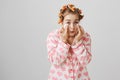 Mirror see even our worst times. Portrait of funny cute caucasian girl in hair curlers and pyjamas looking in mirror Royalty Free Stock Photo