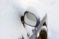 Mirror of snow-covered car