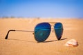 The mirror sunglasses on the beach, the shell and stormy sea are reflected in the glasses Royalty Free Stock Photo