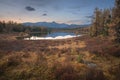 Mirror Surface Lake Autumn Landscape With Mountain Range On Background With Light Pink Sky