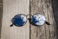 Mirrored sunglasses close up on the wooden pier with clouds and sky reflection Royalty Free Stock Photo