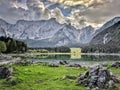 Mirroring mountain in clear blue Lago di Fusine Superiore among Julian Alps in cloudy day