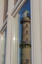 Mirroring of the old lighthouse of Rostock Warnemuende in a window glass