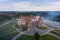 Mirsky Castle and its reflection in the lake in summer. Sunset in cloudy weather with rain clouds. Aerial view from a drone Royalty Free Stock Photo